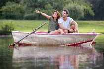 Junges Paar sitzt in einem Ruderboot auf dem See und blickt in die Ferne — Stockfoto