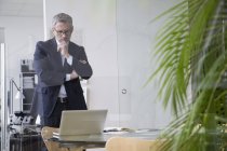 Erfolgreicher Geschäftsmann steht mit Laptop im Vorstandszimmer — Stockfoto