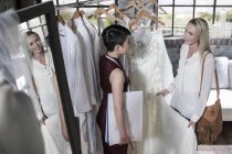 Diseñador de vestido de novia y novia de pie en la tienda nupcial - foto de stock