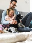 Father and daughter petting dog at home — Stock Photo