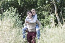 Young man carrying his girlfriend piggyback in the nature — Stock Photo