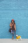 Mujer con su bulldog francés frente a la pared azul - foto de stock