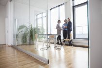 Tre donne d'affari che discutono alla finestra in un ufficio moderno — Foto stock