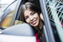 Morena mulher sentada no carro olhando através da janela — Fotografia de Stock