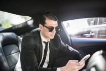 Empresario en coche usando teléfono celular - foto de stock