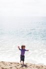 Joyeux petit garçon dansant sur la plage en bord de mer — Photo de stock