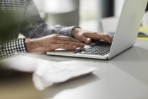 Jovem usando laptop na mesa no escritório — Fotografia de Stock
