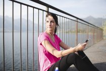 Italia, Lecco, giovane sportiva in riva al lago ad ascoltare musica — Foto stock