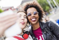 Zwei Frauen, die beim Selfie mit dem Smartphone die Zunge herausstrecken — Stockfoto