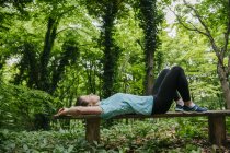 Jeune femme relaxante sur banc en forêt — Photo de stock