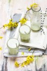 Latte matcha végétalien avec brindilles forsythia et bouteille en verre — Photo de stock