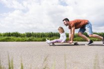 Padre spingendo figlia su skateboard — Foto stock