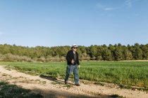 Senior geht mit Stöcken auf Feld — Stockfoto