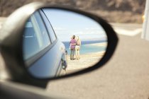 Reflexão de família na costa no espelho de asa de um carro — Fotografia de Stock