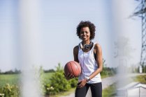 Усміхнена молода жінка тримає баскетбол — стокове фото
