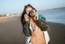 Young woman taking photos on the beach — Stock Photo