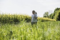 Agricultor segurando enxada no campo de estupro — Fotografia de Stock