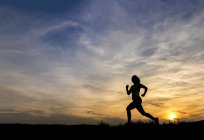 Silhouette of female jogger at sunset — Stock Photo