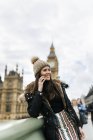 Reino Unido, Londres, joven feliz telefoneando con teléfono inteligente frente al Palacio de Westminster - foto de stock