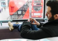 Великобританія, Лондон, молодий чоловік у двоповерхового автобуса, використовуючи його smartwatch — стокове фото