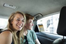 Porträt einer grinsenden Frau, die mit ihrem Freund im Hintergrund im Taxi sitzt — Stockfoto