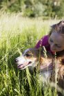 Adolescente con su perro en un prado - foto de stock