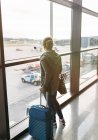 Donna in attesa di imbarcarsi con valigia in aeroporto — Foto stock