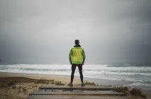 Jogger in piedi sulla spiaggia in una giornata tempestosa, Valdovino, Galizia, Spagna
. — Foto stock