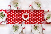 Laid table settings with hearts and red roses — Stock Photo