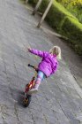 Vista posteriore della bambina in equilibrio sul suo scooter — Foto stock