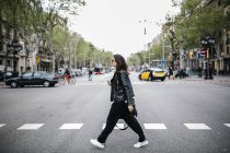 Spain, Barcelona, young woman in the city crossing street — Stock Photo