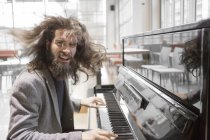 Young hipster man with long hair playing piano — Stock Photo