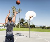 Молодой человек тренируется на открытой баскетбольной площадке — стоковое фото