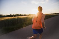 Young man jogging, against the sun — Stock Photo