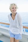 Portrait of blond woman standing at the railing of a cruise ship — Stock Photo