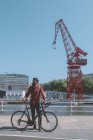 Spain, Bilbao, man and his racing cycle in front of harbour crane — Stock Photo