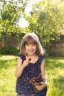 Porträt eines lachenden kleinen Mädchens mit Kirschen im Garten — Stockfoto