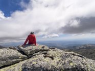 Spagna, Sierra de Gredos, Veduta posteriore dell'escursionista seduto sulla roccia, paesaggio panoramico delle montagne sullo sfondo — Foto stock