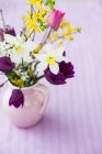 Ramo de flores frescas de primavera cortadas en jarrón sobre fondo rosa — Stock Photo