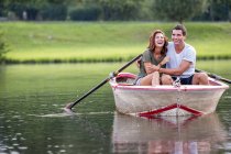 Jeune couple s'amusant dans un bateau à rames sur le lac — Photo de stock