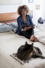 Mujer con gato sosteniendo tableta digital - foto de stock
