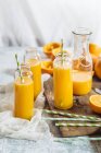 Arance affettate e bottiglie di vetro di succo d'arancia appena spremuto — Foto stock