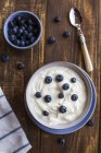 Top view of yogurt with blueberries in bowls on wood — Stock Photo