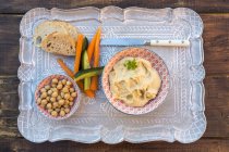Hummus, chick peas, carrots, cucumber, baguette on tray — Stock Photo
