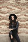 Giovane donna alla moda indossando cappello nero in piedi davanti alla facciata — Foto stock