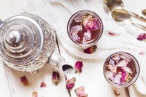 Teekanne und zwei Gläser Rosenblütentee mit getrockneten Rosenblüten — Stockfoto