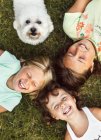 Tre bambine con un cucciolo sdraiato sull'erba — Foto stock