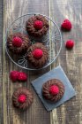 Mini cakes with raspberries on cooling grid and slate — Stock Photo