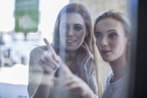Giovani donne che guardano attraverso la finestra del negozio — Foto stock