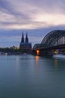 Німеччина, Кельн, вид на Кельнський собор з Гогенцоллерн міст на передньому плані в вечірні сутінки — стокове фото